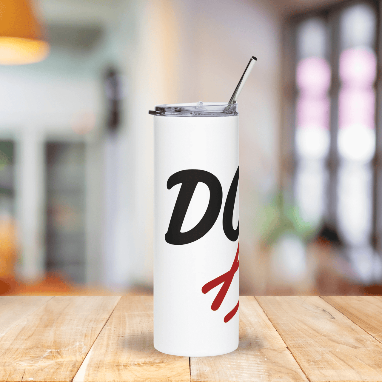 White tumbler with black and red design on a wooden table with a blurred background