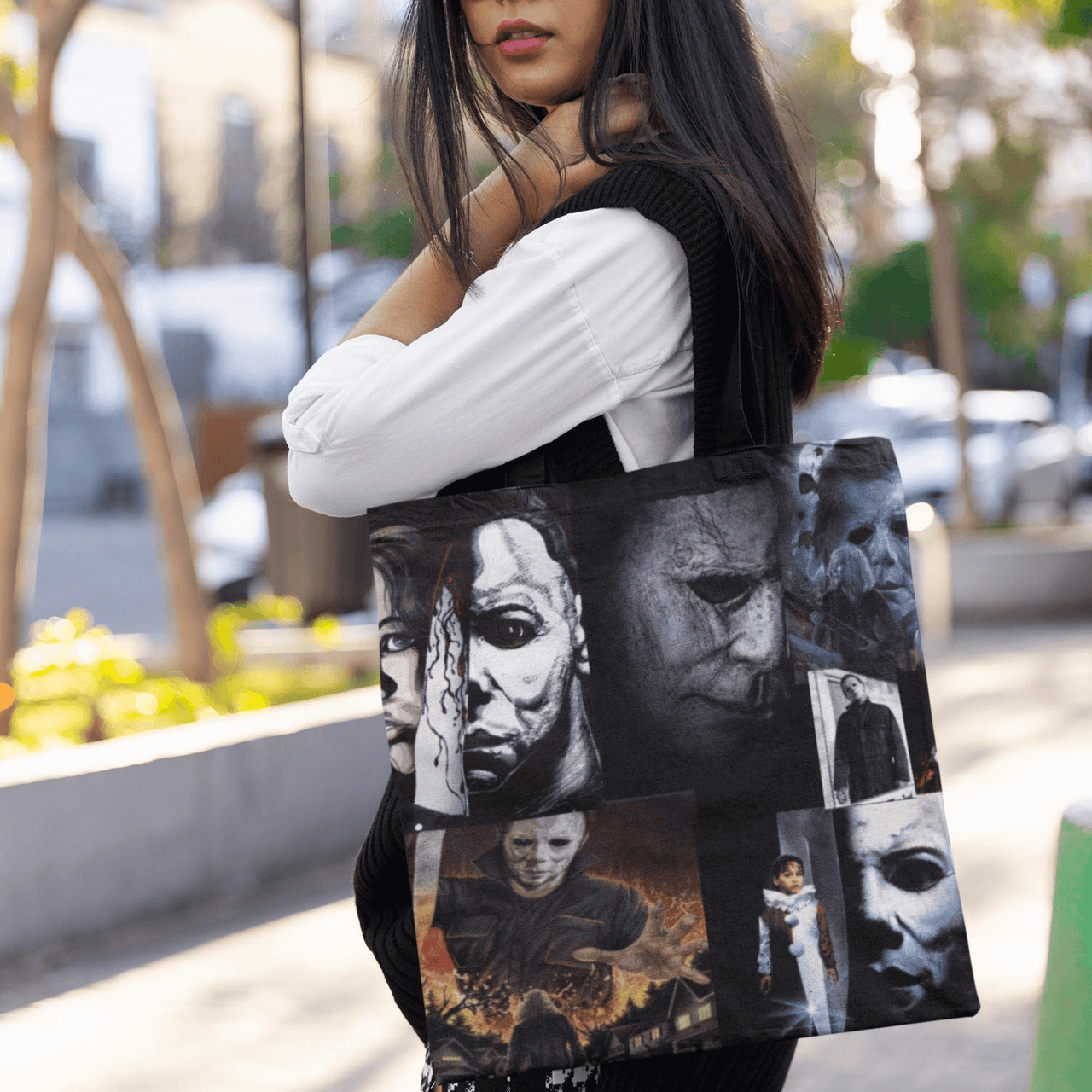 Person holding a tote bag with multiple images of a character outdoors.
