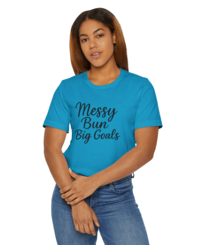 Person wearing a blue t-shirt with 'Messy Bun Big Goals' text on a white background