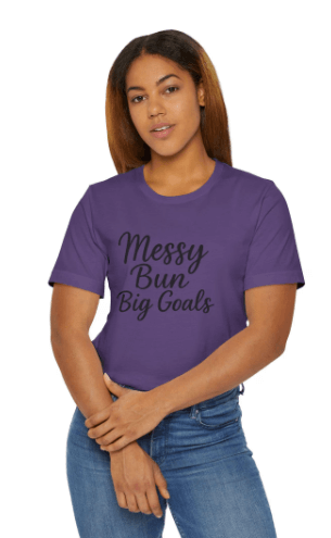 Person wearing a purple t-shirt with 'Messy Bun Big Goals' text on a white background