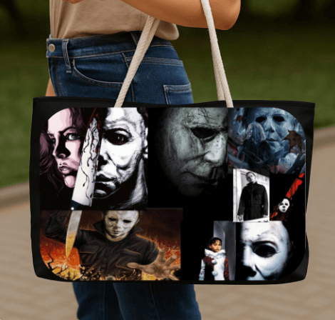 Tote bag with multiple face designs held by a person outdoors.