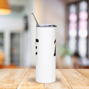 White tumbler with black design on a wooden table with a blurred background