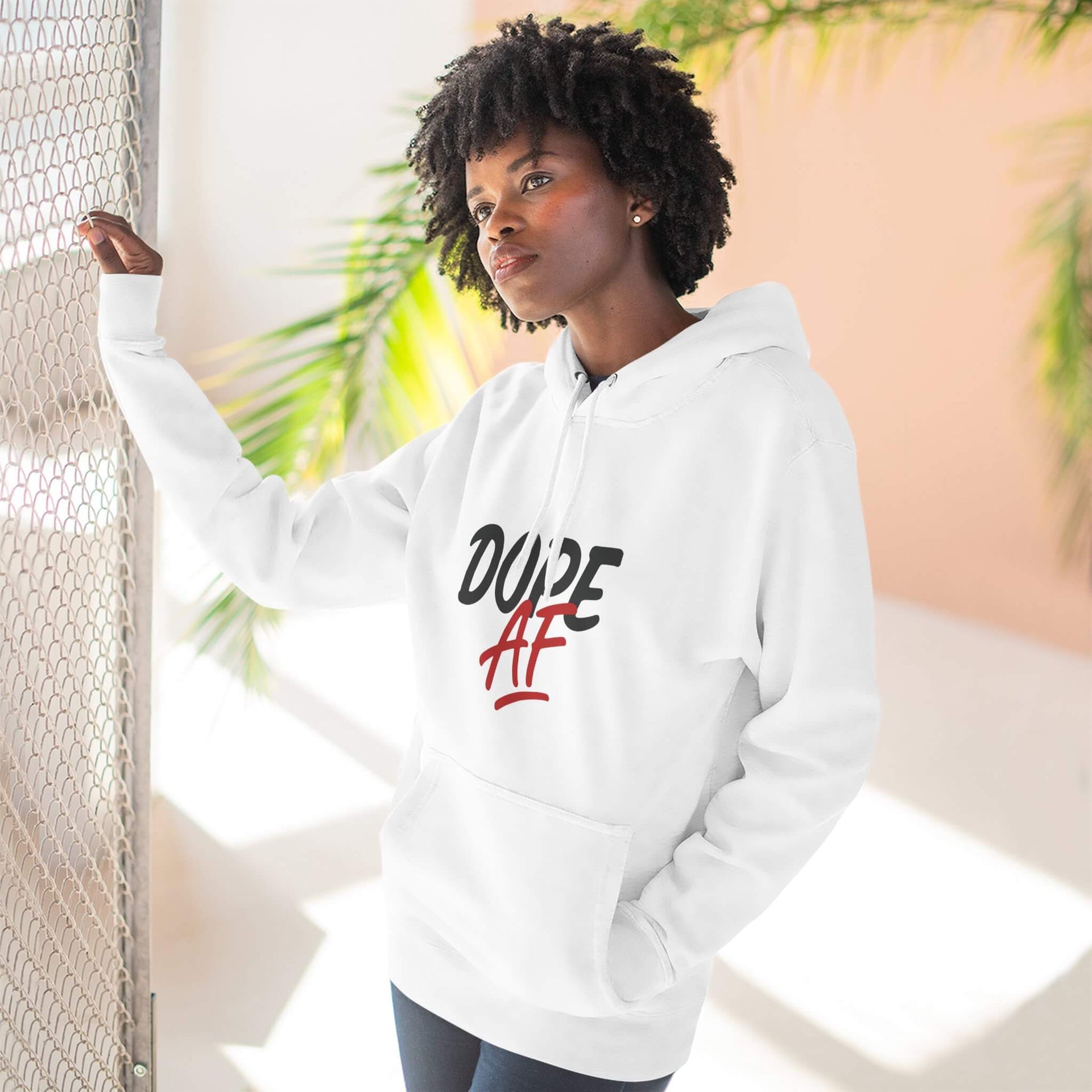 Person wearing a white hoodie with 'DOPE AF' text, standing against a light background with plants.