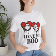 Person wearing a white t-shirt with a graphic design and text, standing indoors.