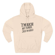 Beige hoodie with text 'I'm rich, my funds just on hold' on a white background