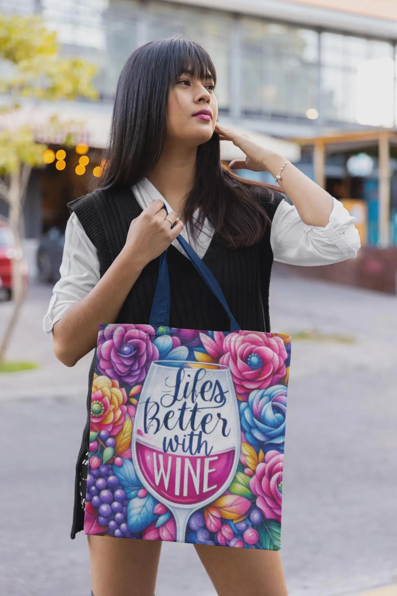 Woman holding a colorful tote bag with floral design and text.