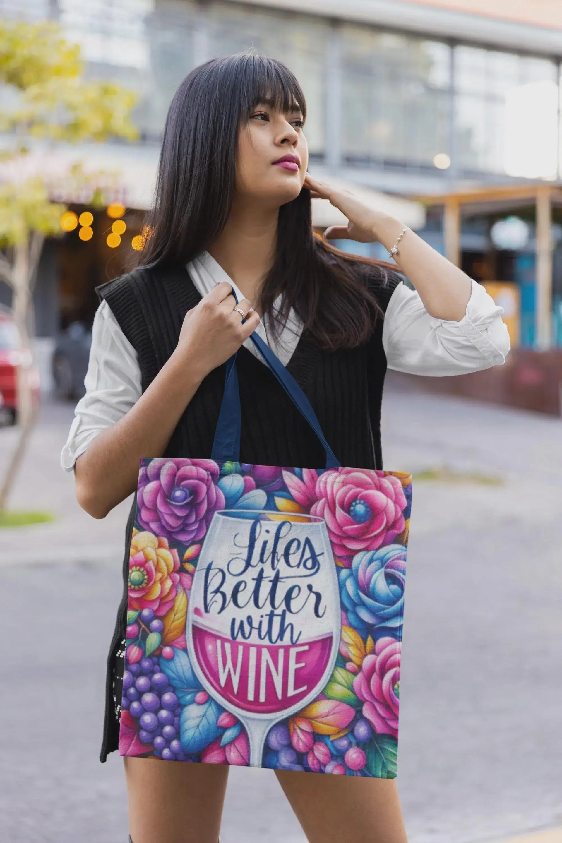 Woman holding a colorful tote bag with floral design and text.
