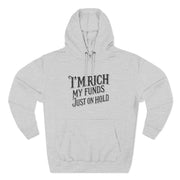 Gray hoodie with text 'I'm rich, my funds just on hold' on a white background