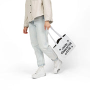 Person holding a tote bag with text on a white background
