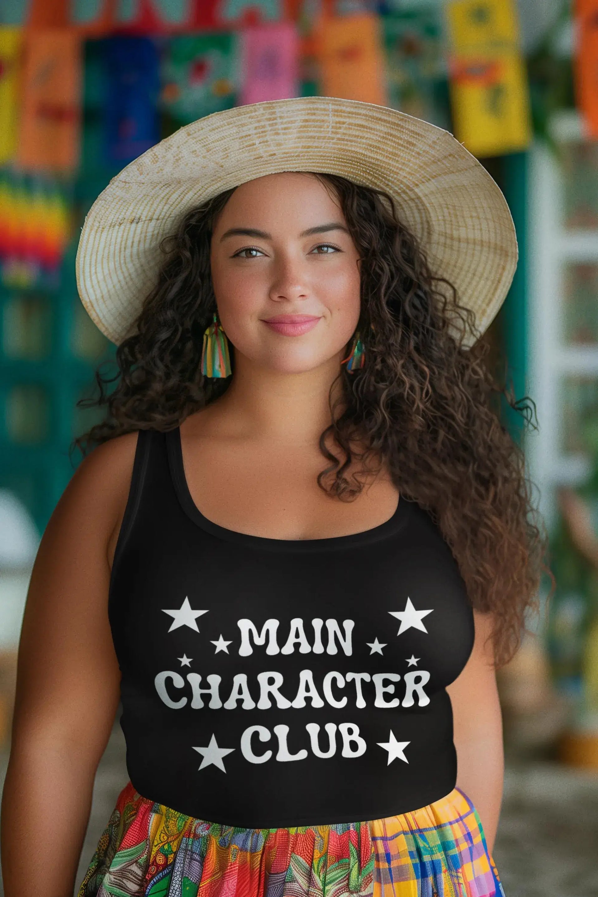 Woman wearing a black tank top with 'MAIN CHARACTER CLUB' text and a colorful hat in front of a vibrant background.