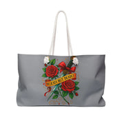 Gray tote bag with red roses, a bow, and 'Delicate But Deadly' text on a white background
