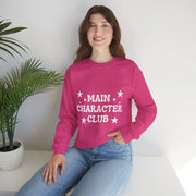 Person wearing a pink sweatshirt with 'MAIN CHARACTÓR CLUB' text, sitting indoors.