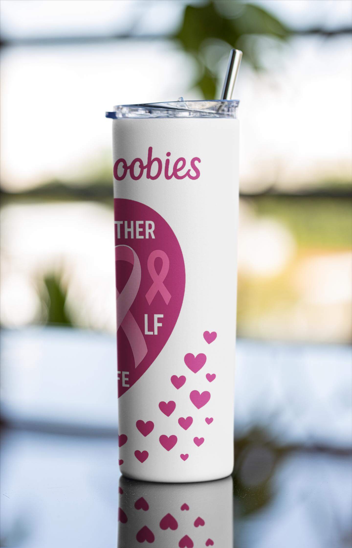 Tumbler with pink ribbon and heart design on a blurred natural background