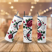 Three white tumblers with floral designs on a wooden surface with a blurred background.