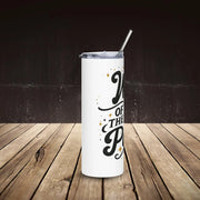 White tumbler with black text and a straw on a wooden surface with a dark background