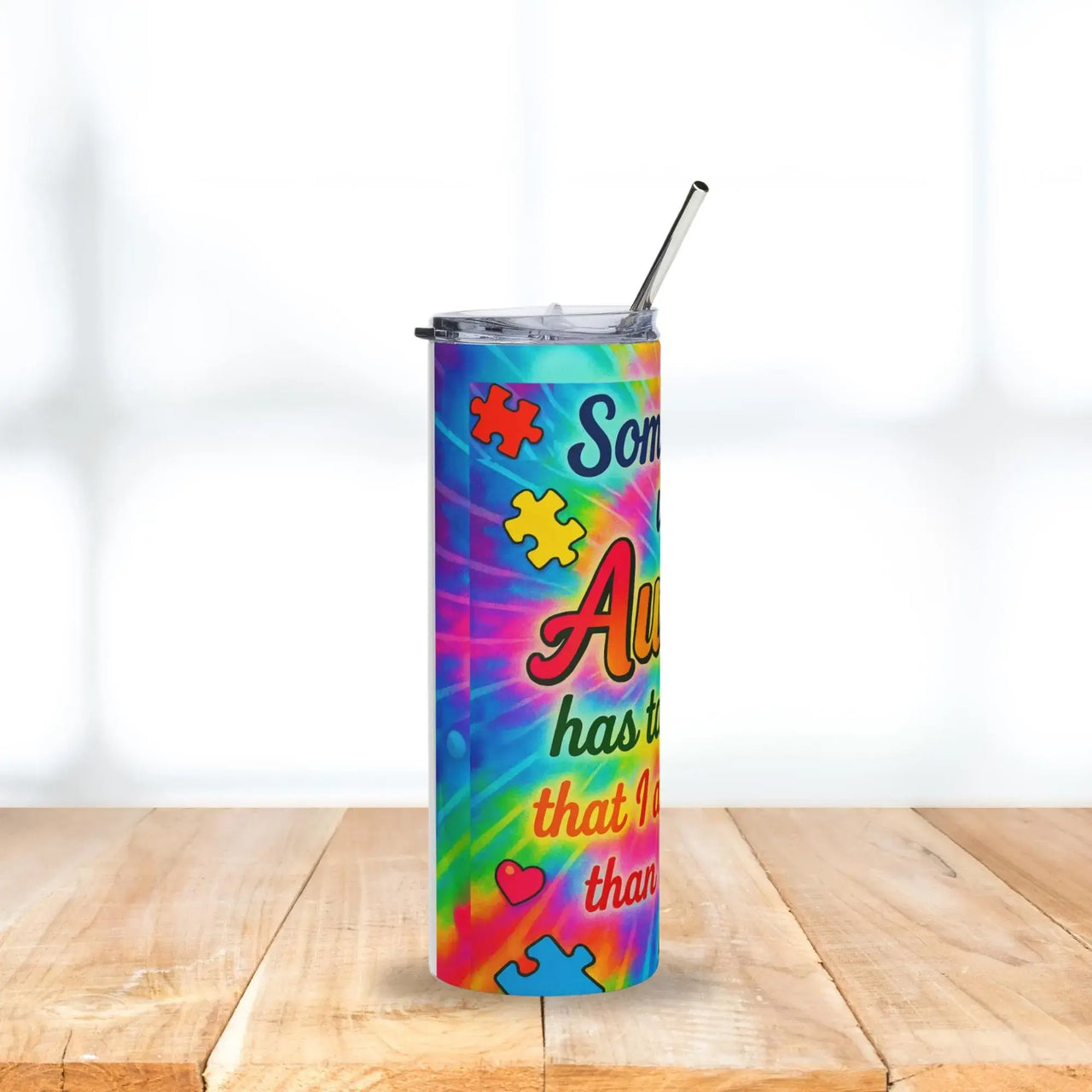 Colorful tumbler with autism awareness design on a wooden surface