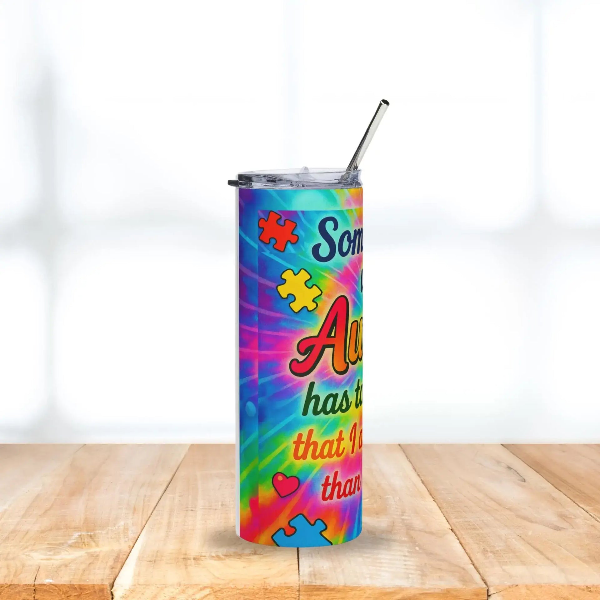 Colorful tumbler with autism awareness design on a wooden surface