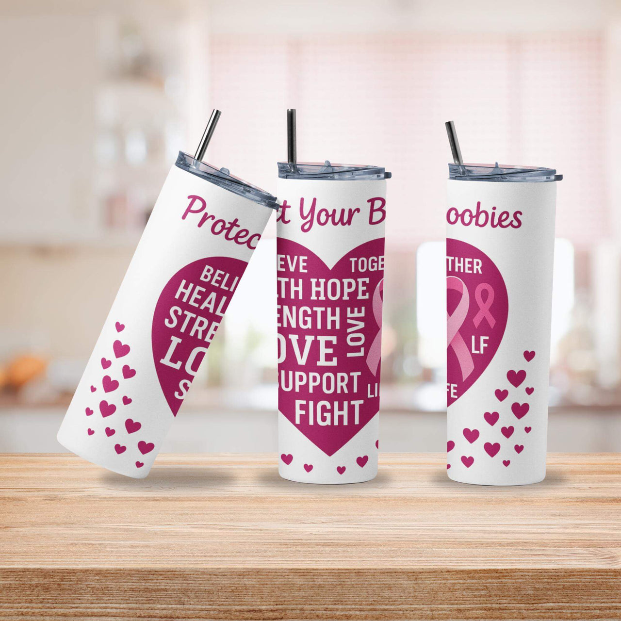 Three tumblers with pink and white designs on a wooden surface.
