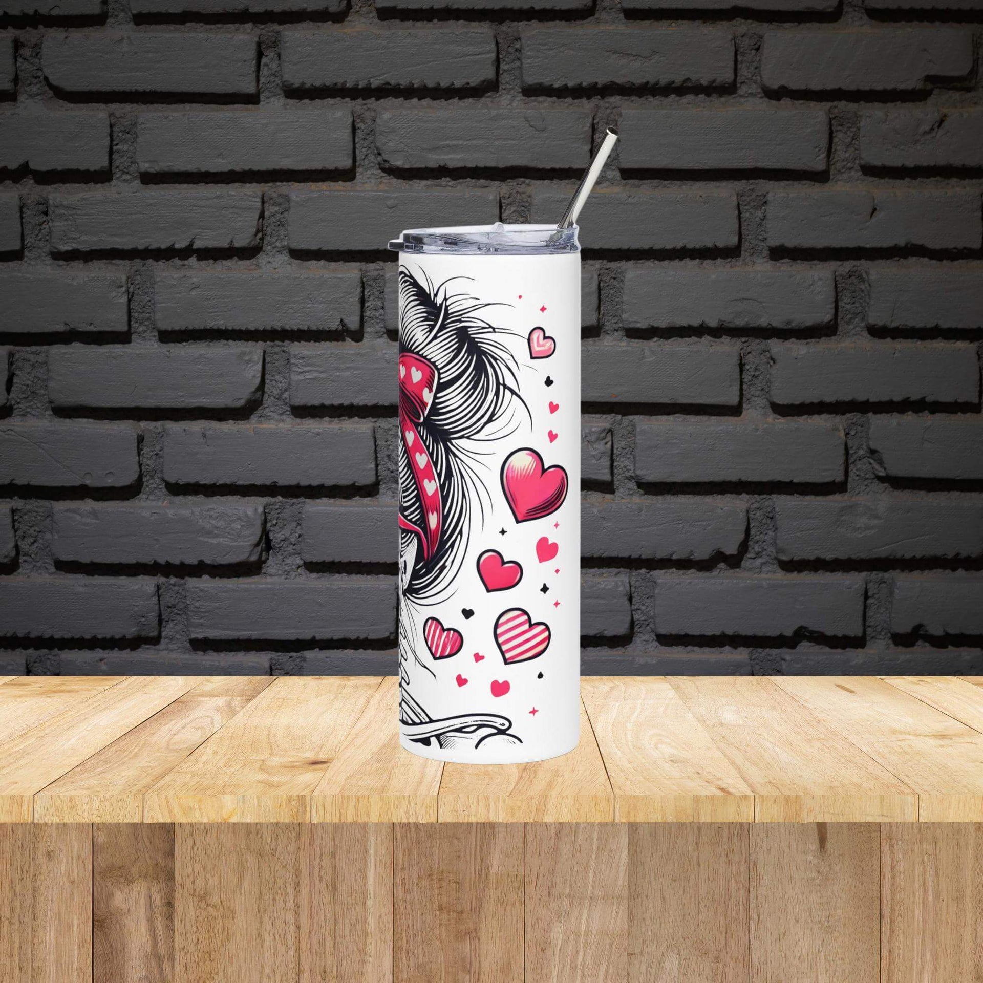 Tumbler with heart and unicorn design on a wooden surface with a black brick wall background
