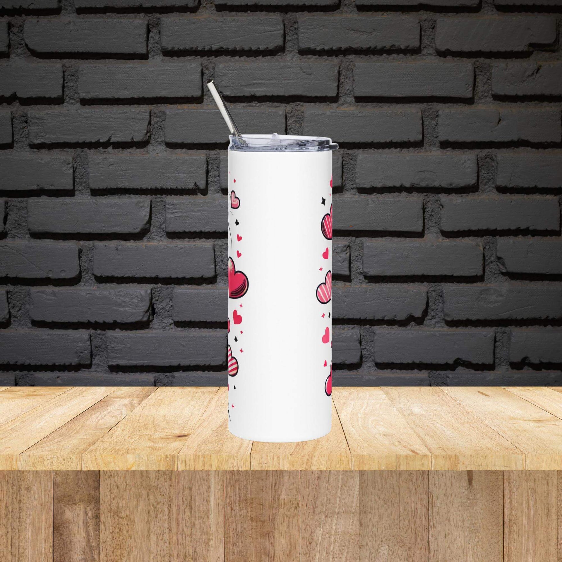 White tumbler with red heart pattern on a wooden surface with black brick wall background