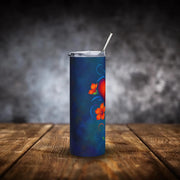 Blue tumbler with floral design on a wooden surface and dark background