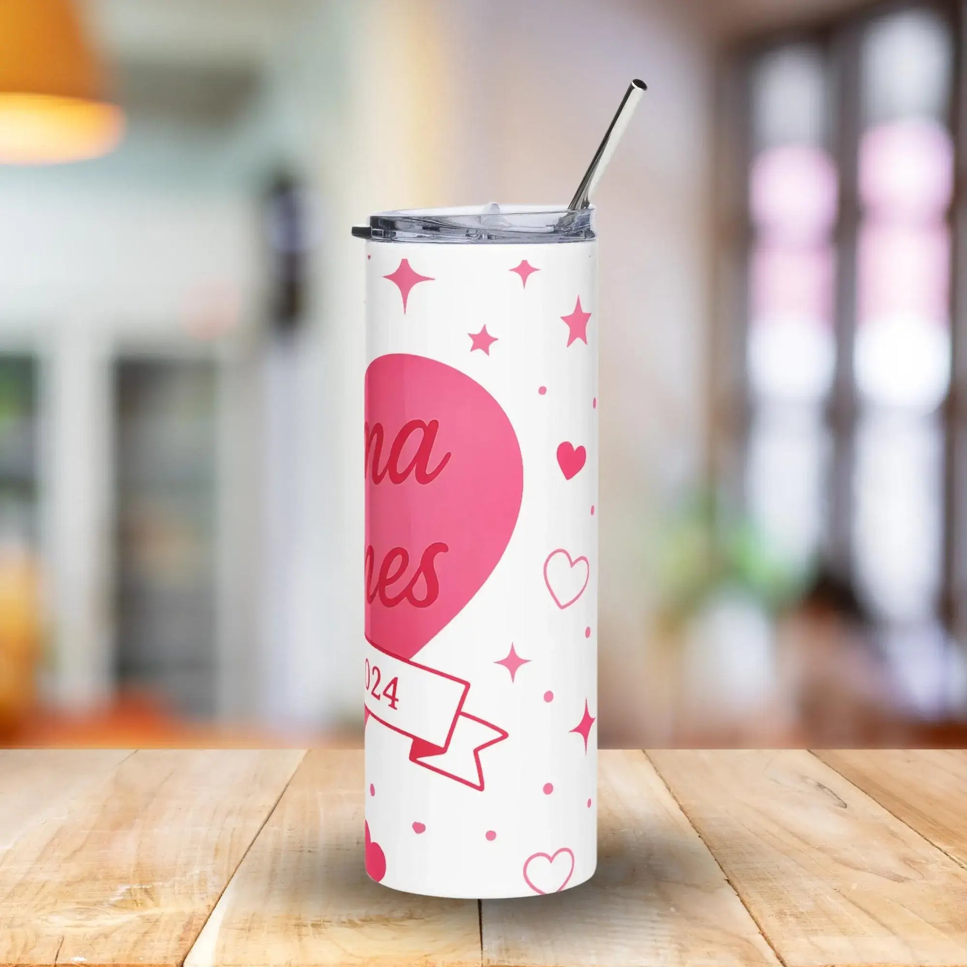 White tumbler with pink heart design on a wooden table