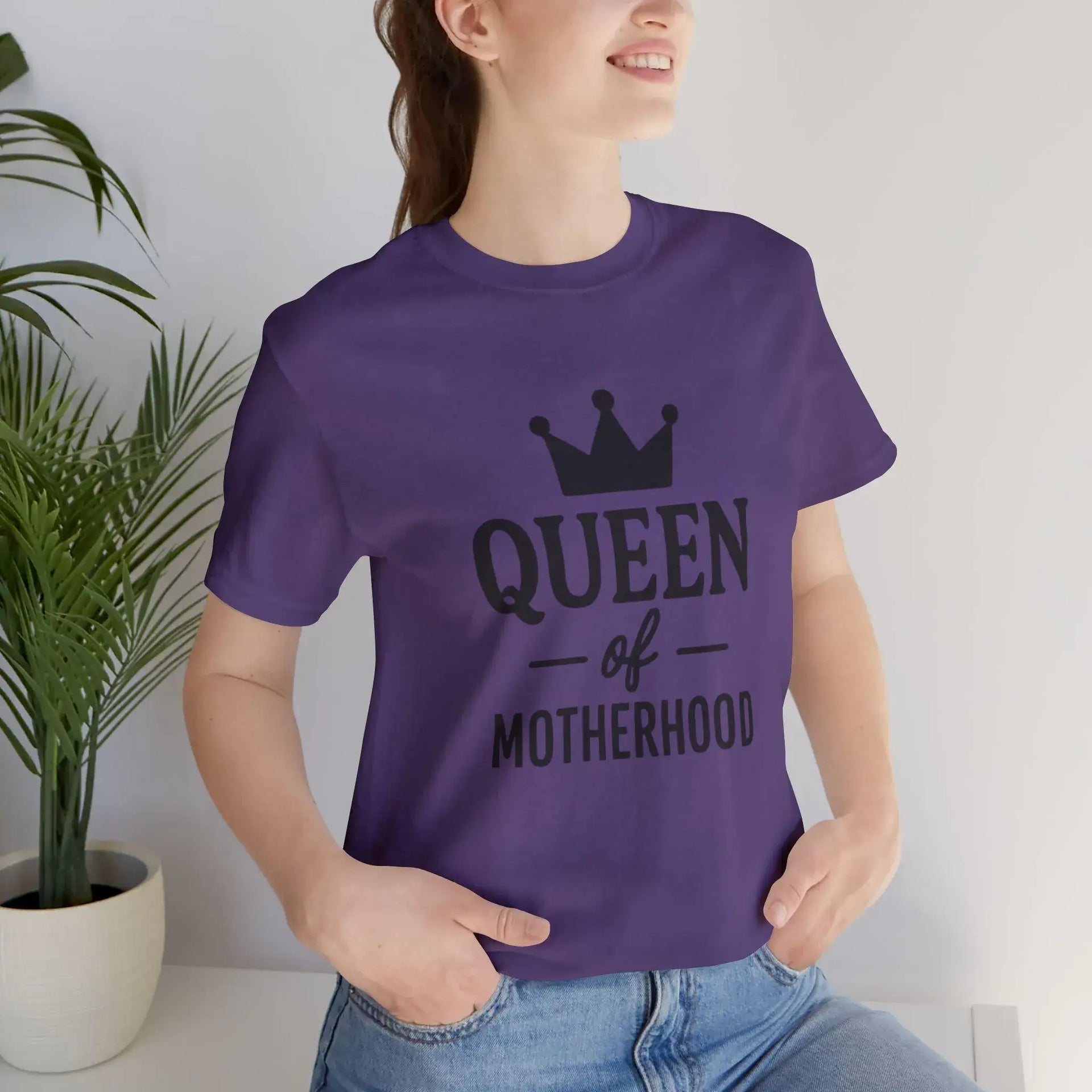 Person wearing a purple t-shirt with 'Queen of Motherhood' text and a crown graphic.