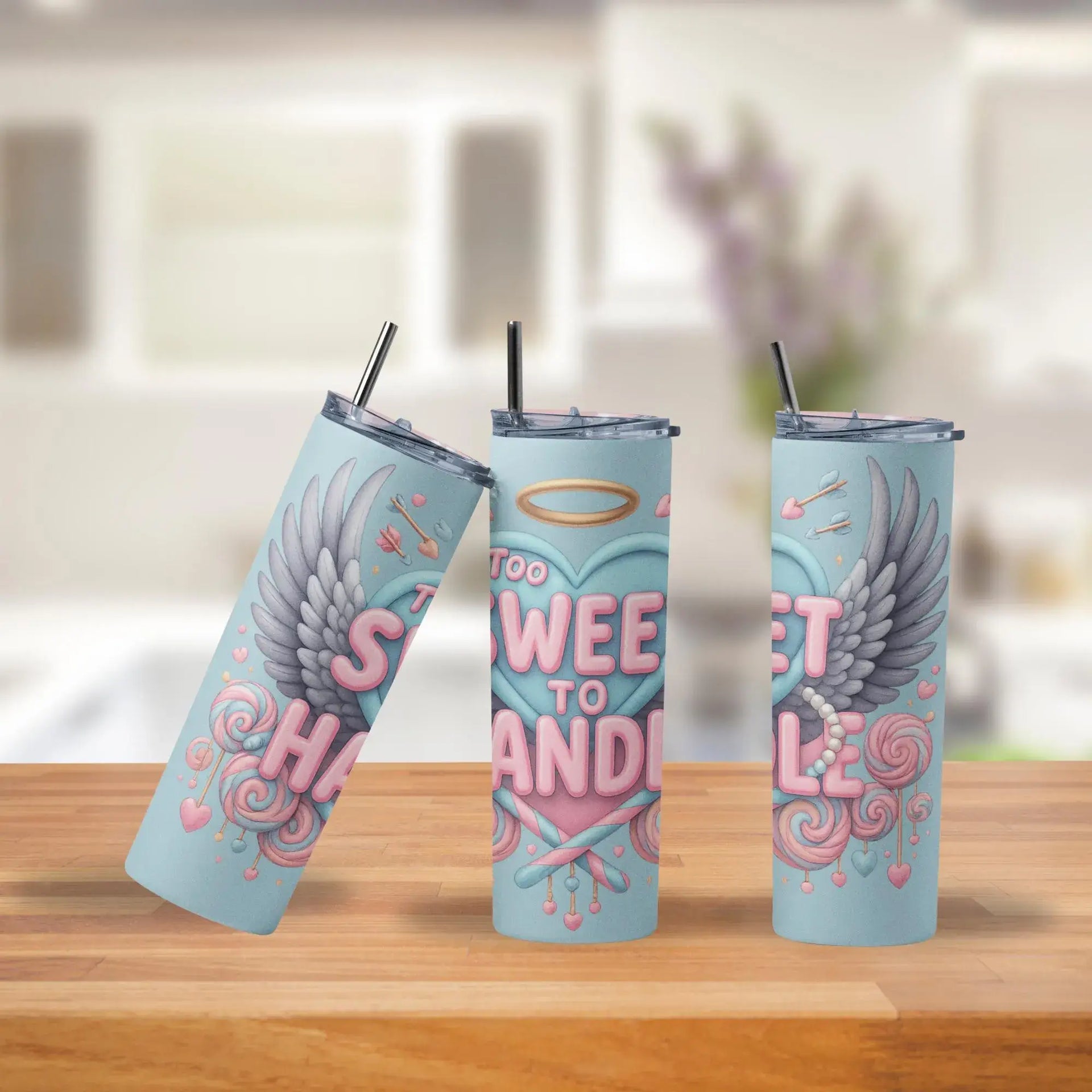 Three insulated tumblers with decorative designs on a wooden surface.