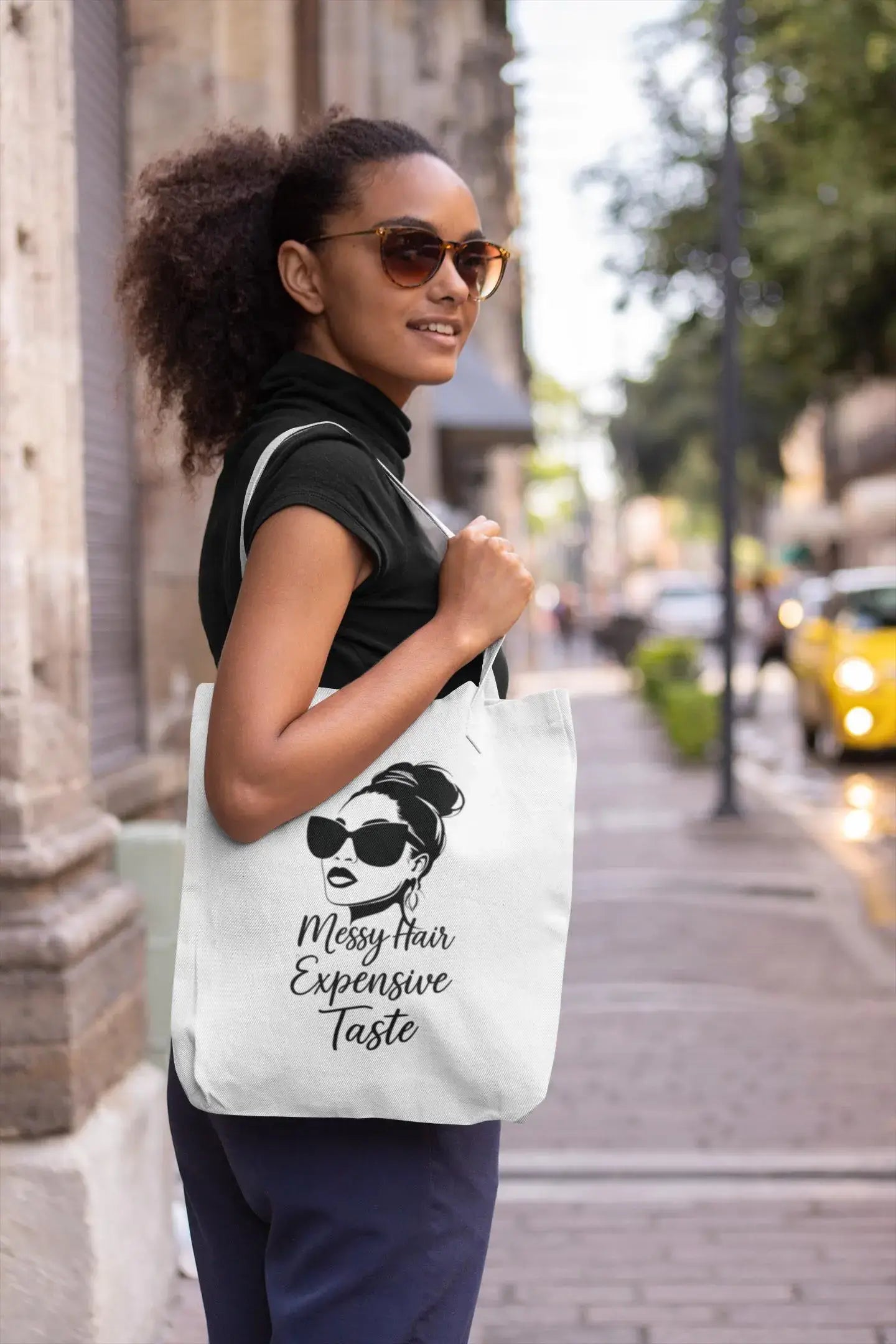 Woman holding a tote bag with a graphic design on a city street