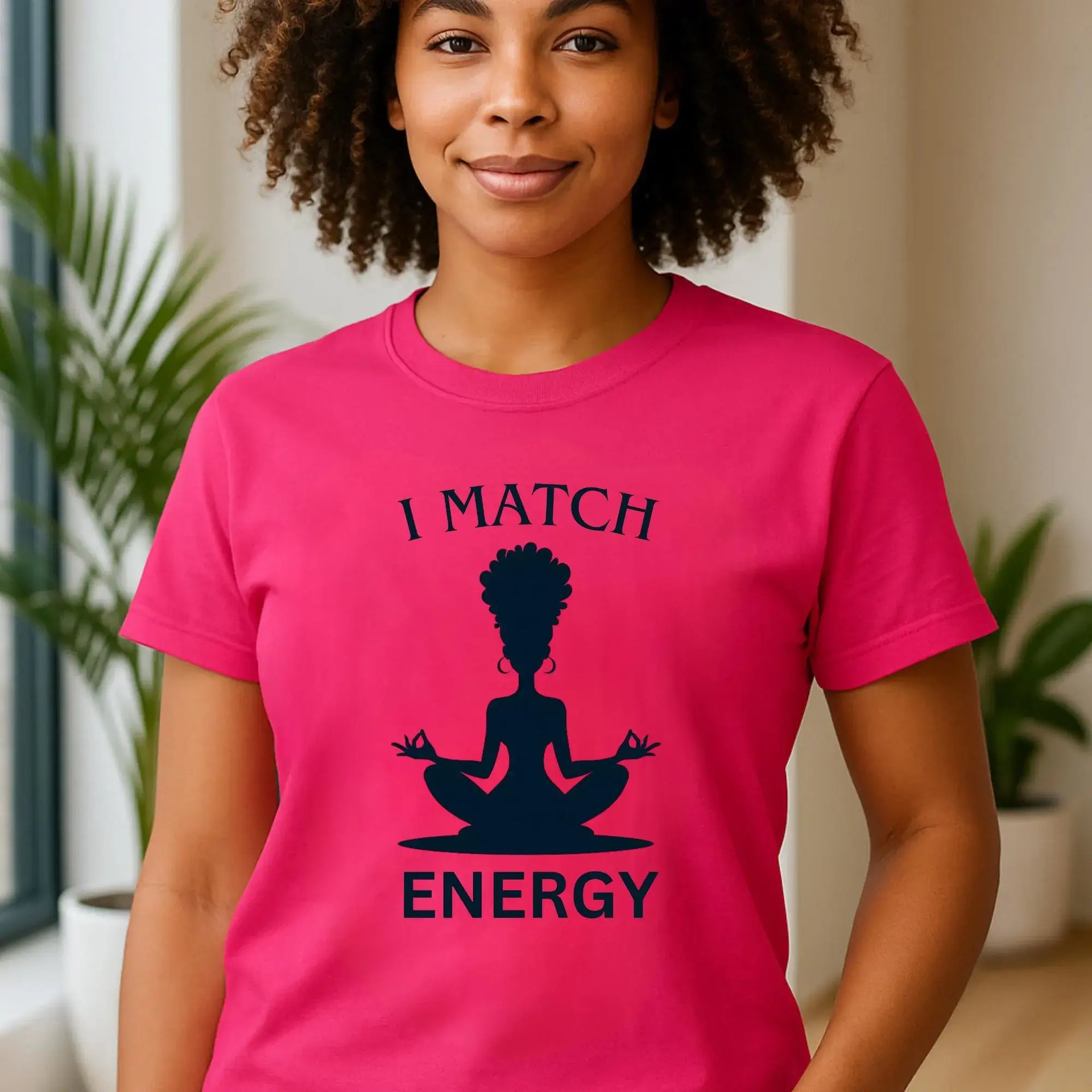 Person wearing a pink t-shirt with a graphic and text 'I MATCH ENERGY' in an indoor setting.