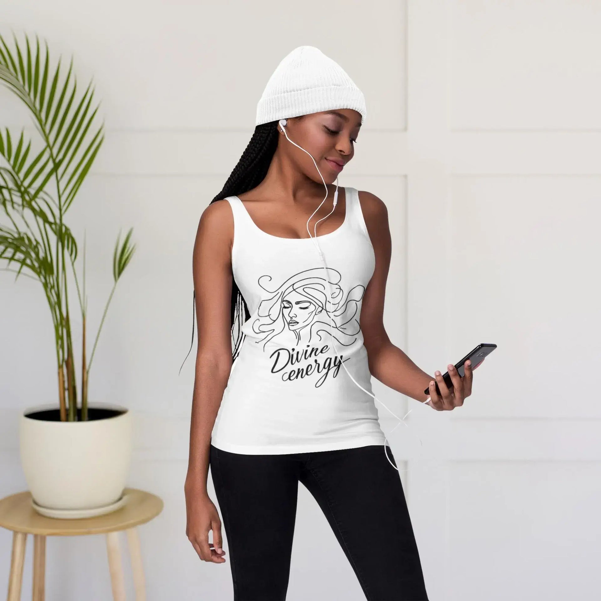 Woman wearing a white tank top with a design and text, standing indoors.