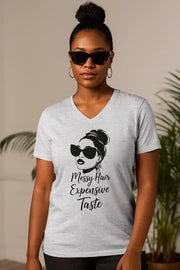 Woman wearing a gray t-shirt with a graphic and text, standing against a neutral background.