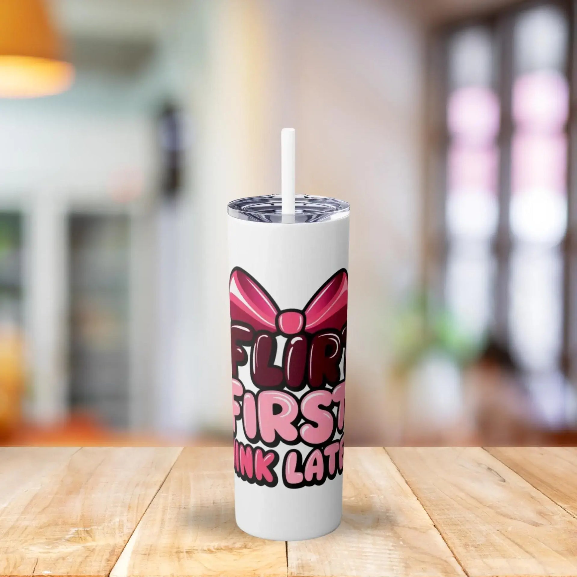 White tumbler with pink and black text and a bow design on a wooden table.