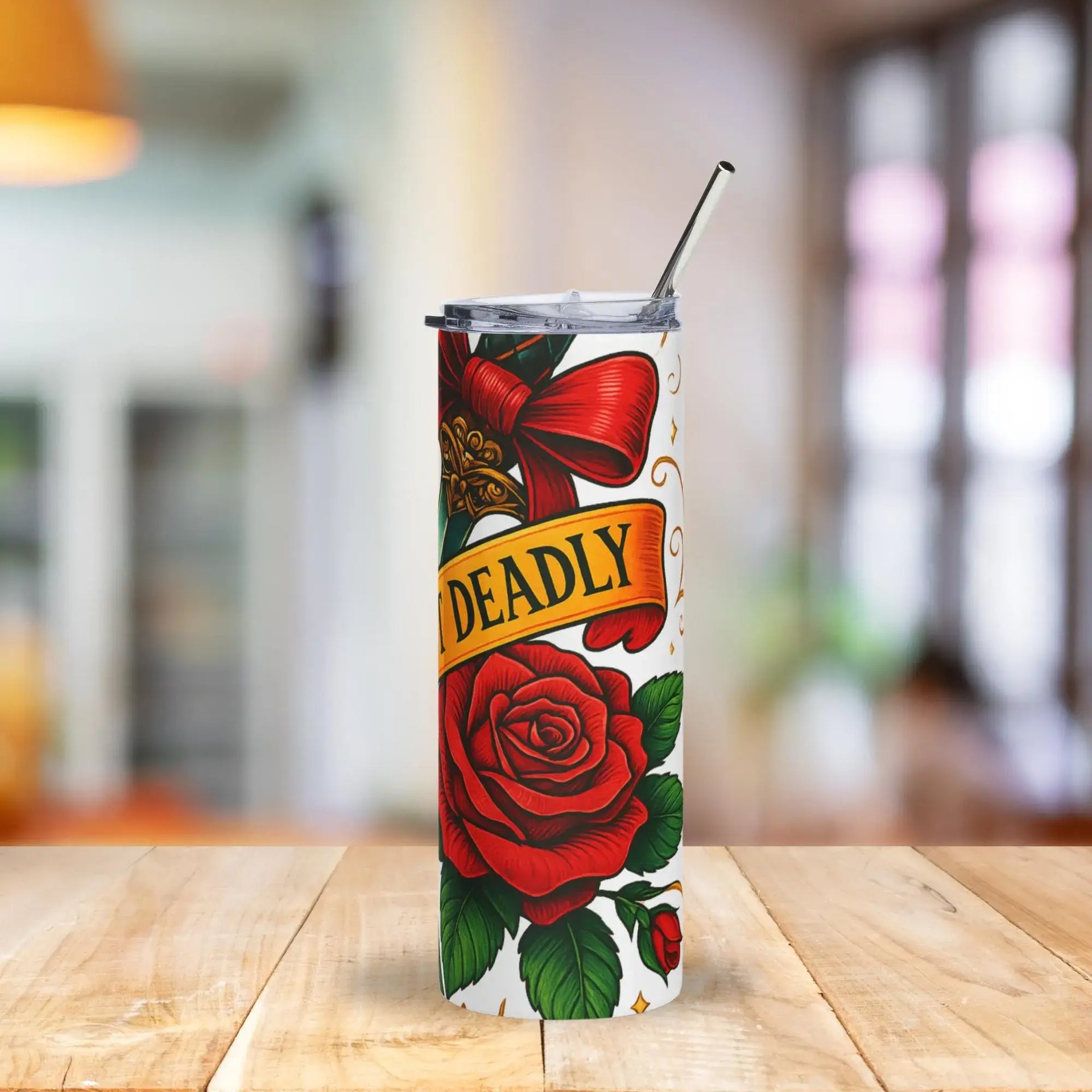 Tumbler with red rose and 'DEADLY' design on a wooden table with a blurred background