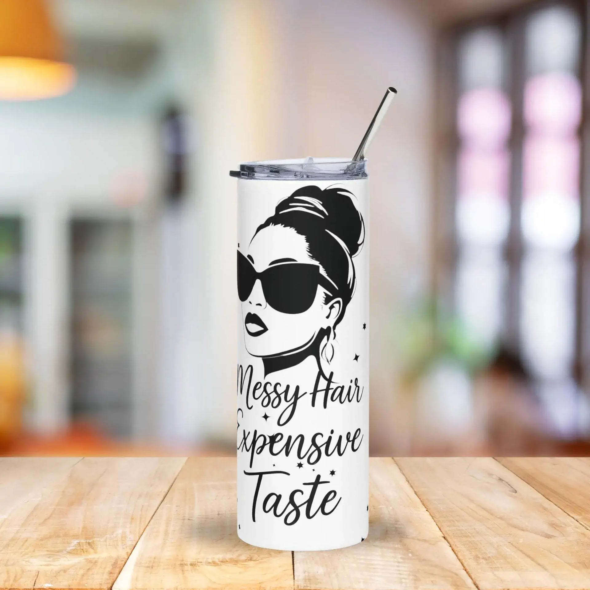 Tumbler with a design of a woman with messy hair and sunglasses, featuring the text 'Messy Hair Expensive Taste', on a wooden table.