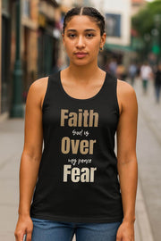 Woman wearing a black tank top with 'Faith Over Fear' text on a city street.