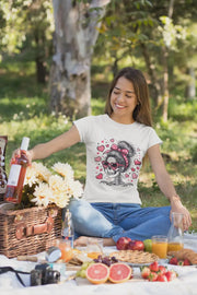 Woman sitting at a picnic with a skull and heart design t-shirt, surrounded by food and drinks.