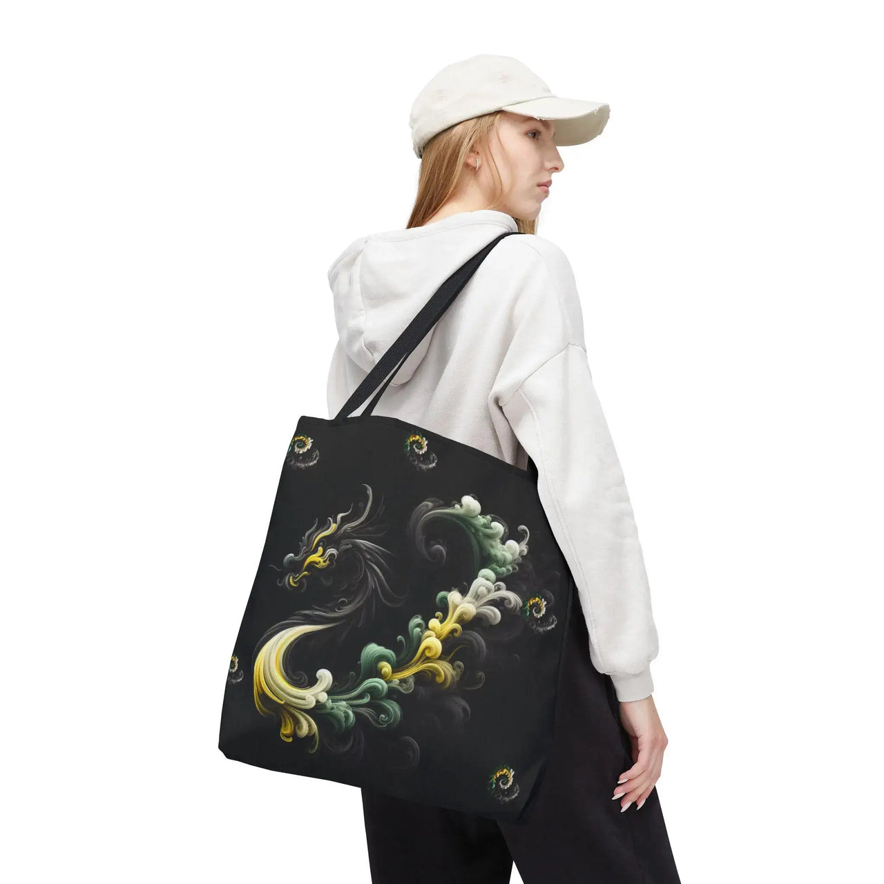 Person wearing a white hoodie and cap, carrying a black tote bag with colorful designs on a white background