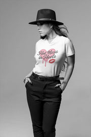Woman wearing a white t-shirt with 'Hot Mess in Heels' text and black pants on a gray background