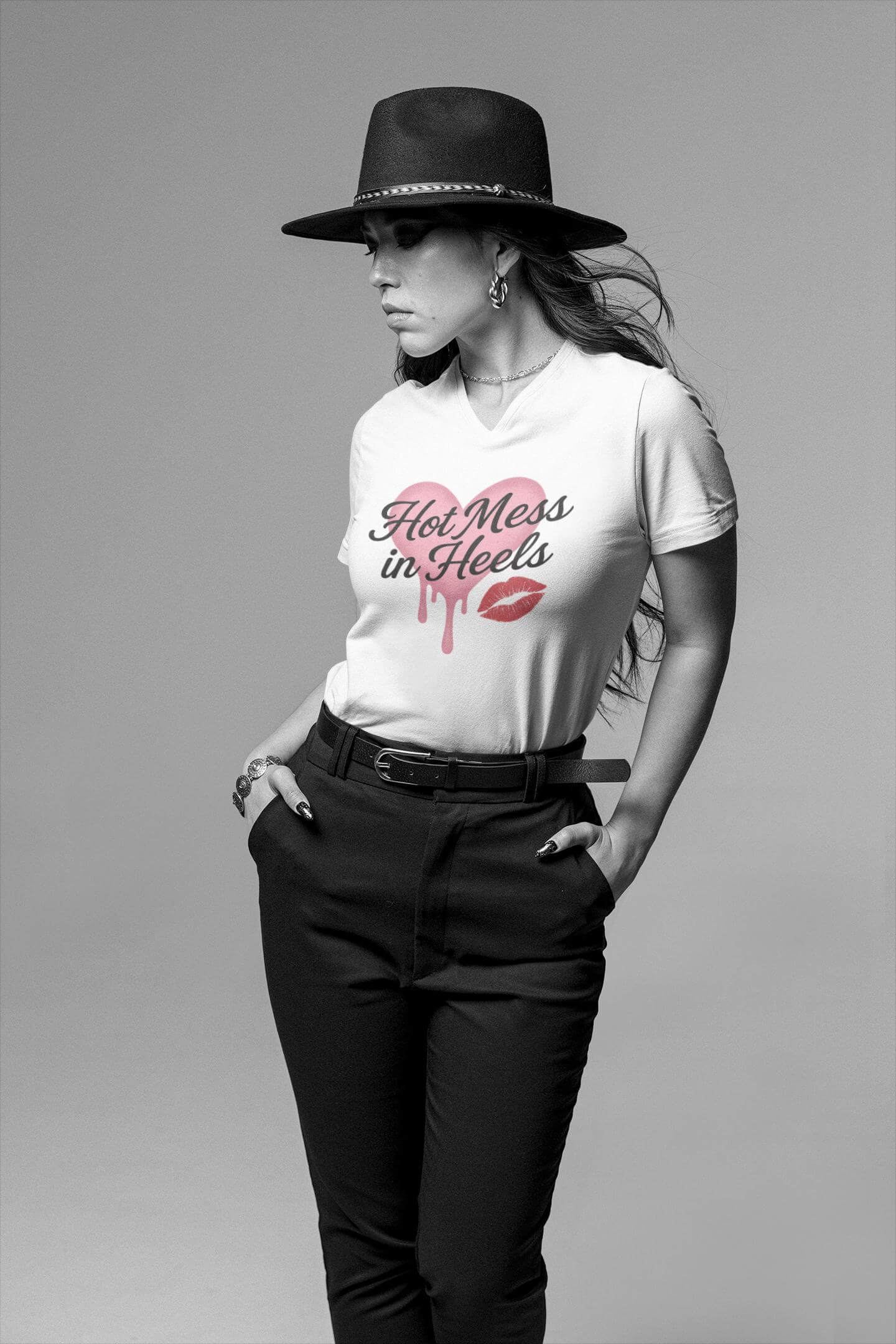 Woman wearing a white t-shirt with 'Hot Mess in Heels' text and black pants on a gray background