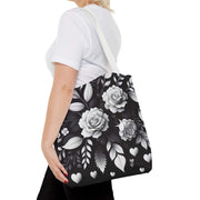 Person holding a black tote bag with white floral design on a white background