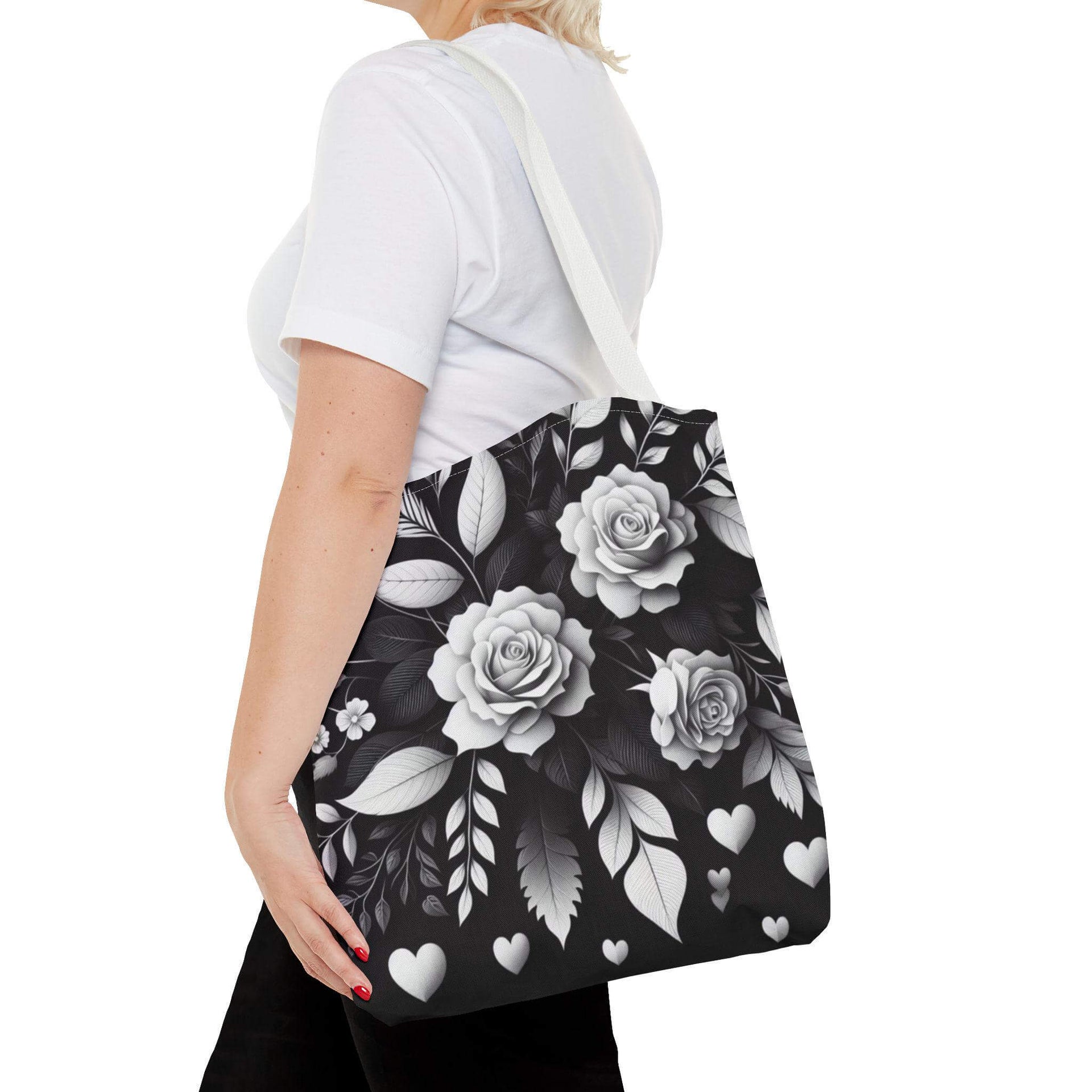 Person holding a black tote bag with white floral design on a white background