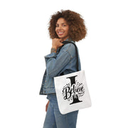 Woman holding a tote bag with 'I Believe' design on a white background