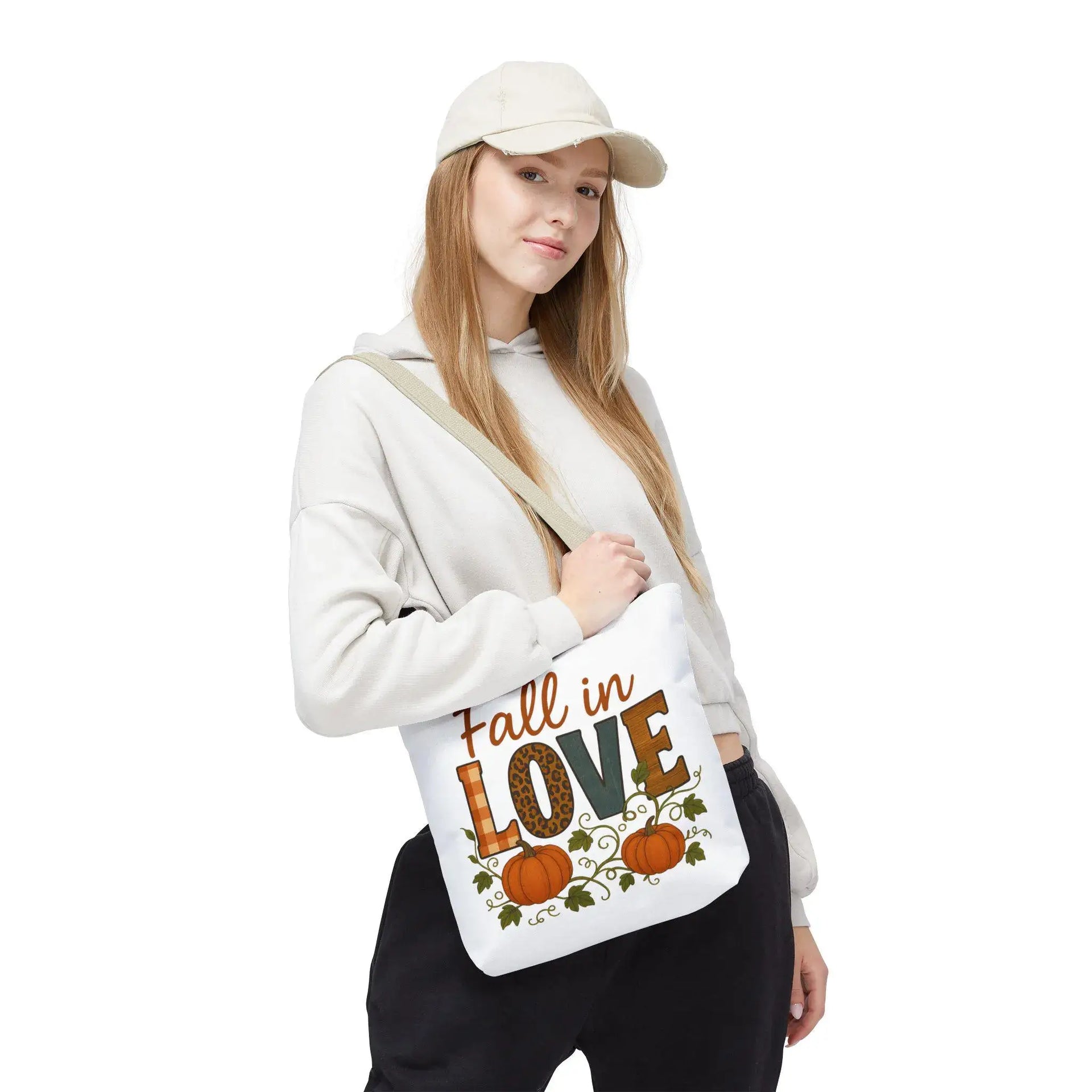 Person holding a tote bag with 'Fall in Love' text and pumpkin design on a white background