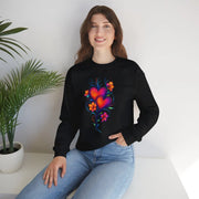 Person wearing a black sweatshirt with a colorful heart design, sitting on a white surface with a plant in the background.