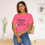 Woman wearing a pink t-shirt with 'Messy Bun Big Goals' text in a living room setting.