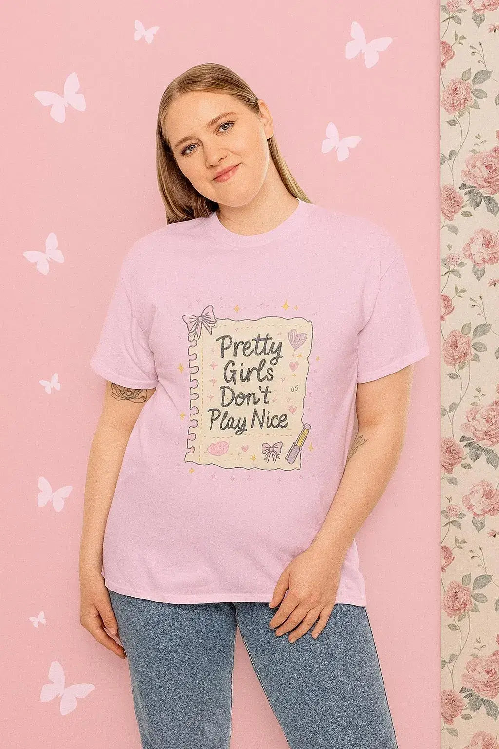 Person wearing a pink t-shirt with 'Pretty Girls Don't Play Nice' text against a pink background with butterflies.