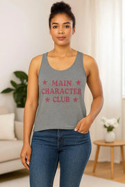 Woman wearing a gray tank top with 'MAIN CHARACTER CLUB' text in a living room setting