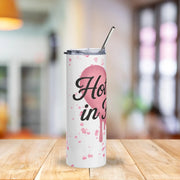 White tumbler with pink design and text on a wooden table