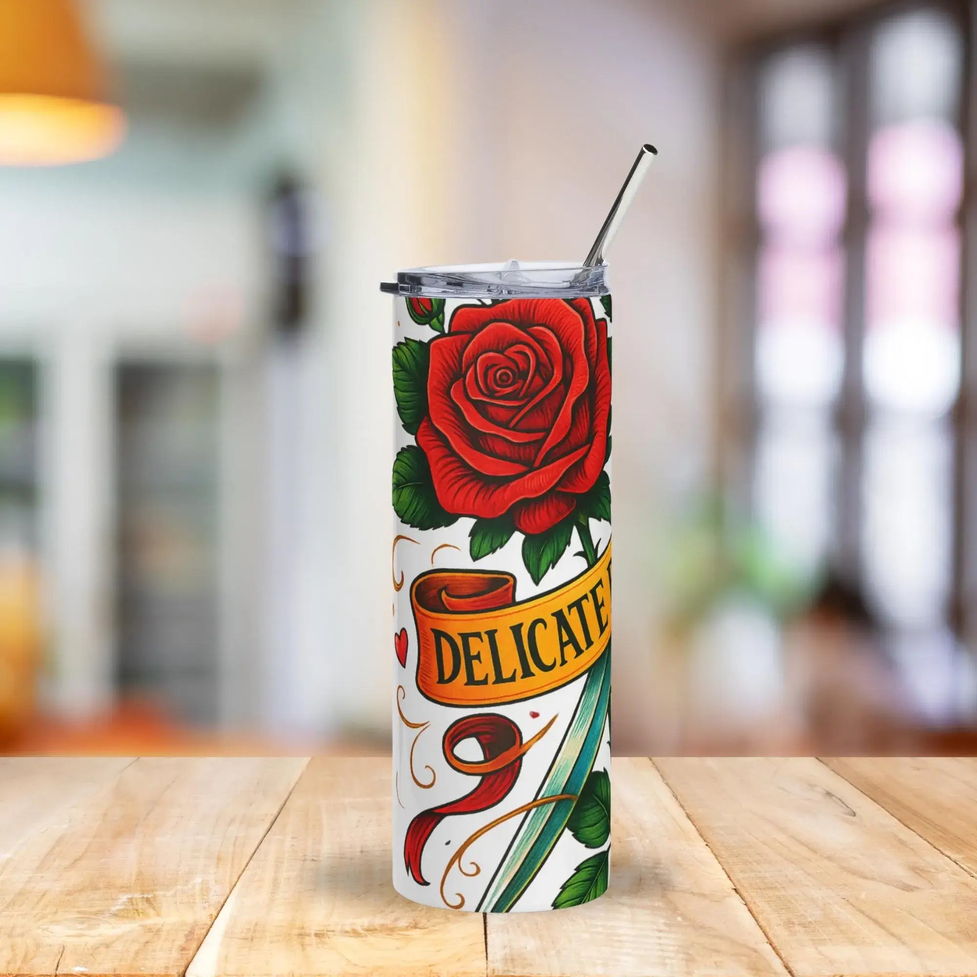 Tumbler with a red rose design and 'Delicate' text on a wooden table.